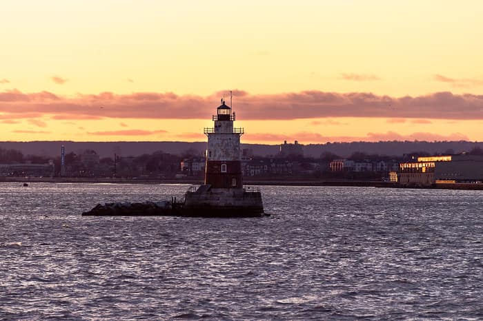 El pequeño faro de Robbins Reef en la bahía de Nueva York al atardecer